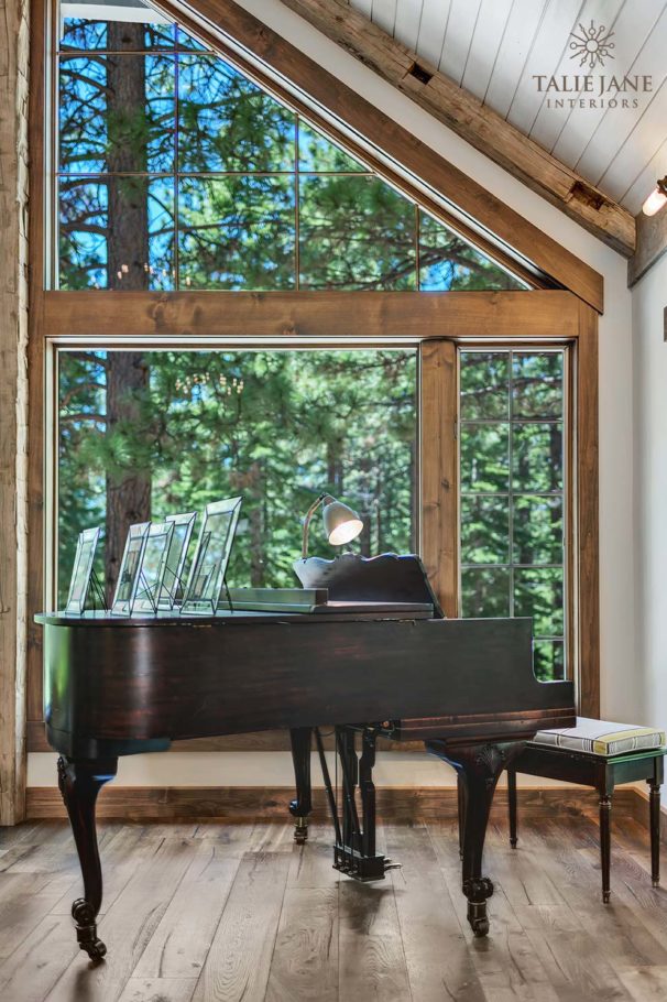 The view of a grand piano placed against a massive glass window